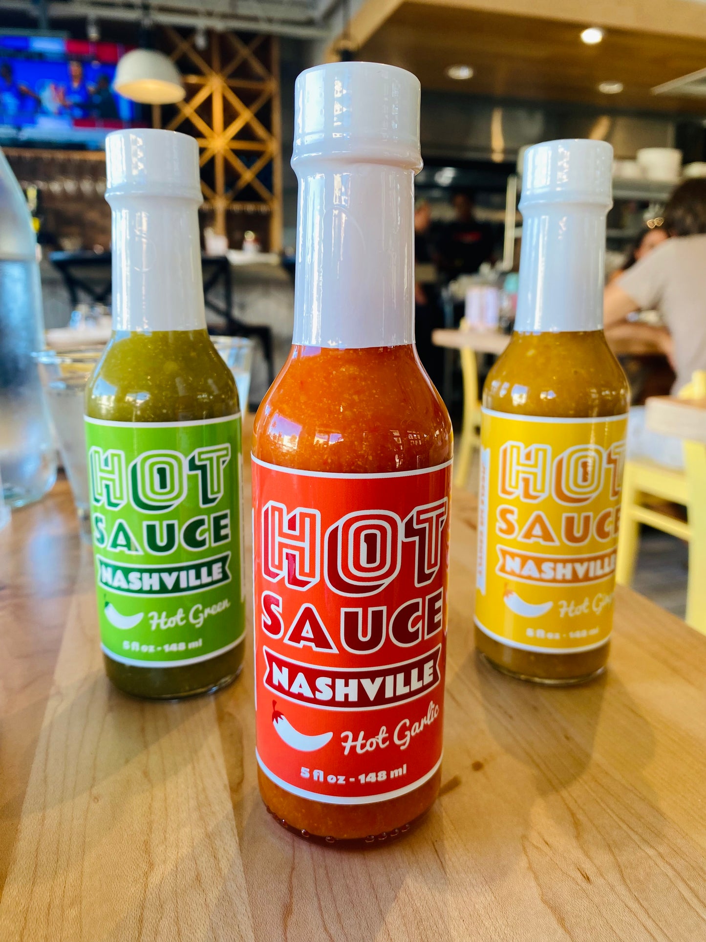Hot Green, Hot Garlic, and Hot Ginger hot sauces on table